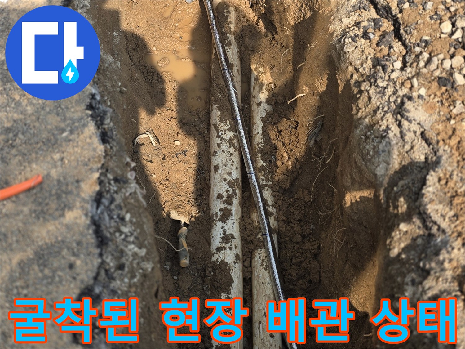 도로 아래 묻혀 있던 배관이 흙과 함께 노출된 장면입니다.