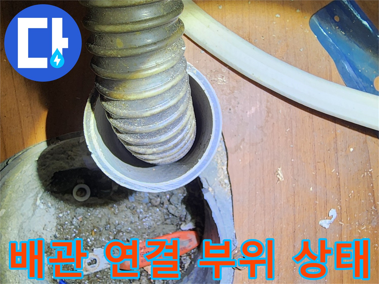 주름진 배관과 주황색 고정 장치가 보이는 사진입니다.