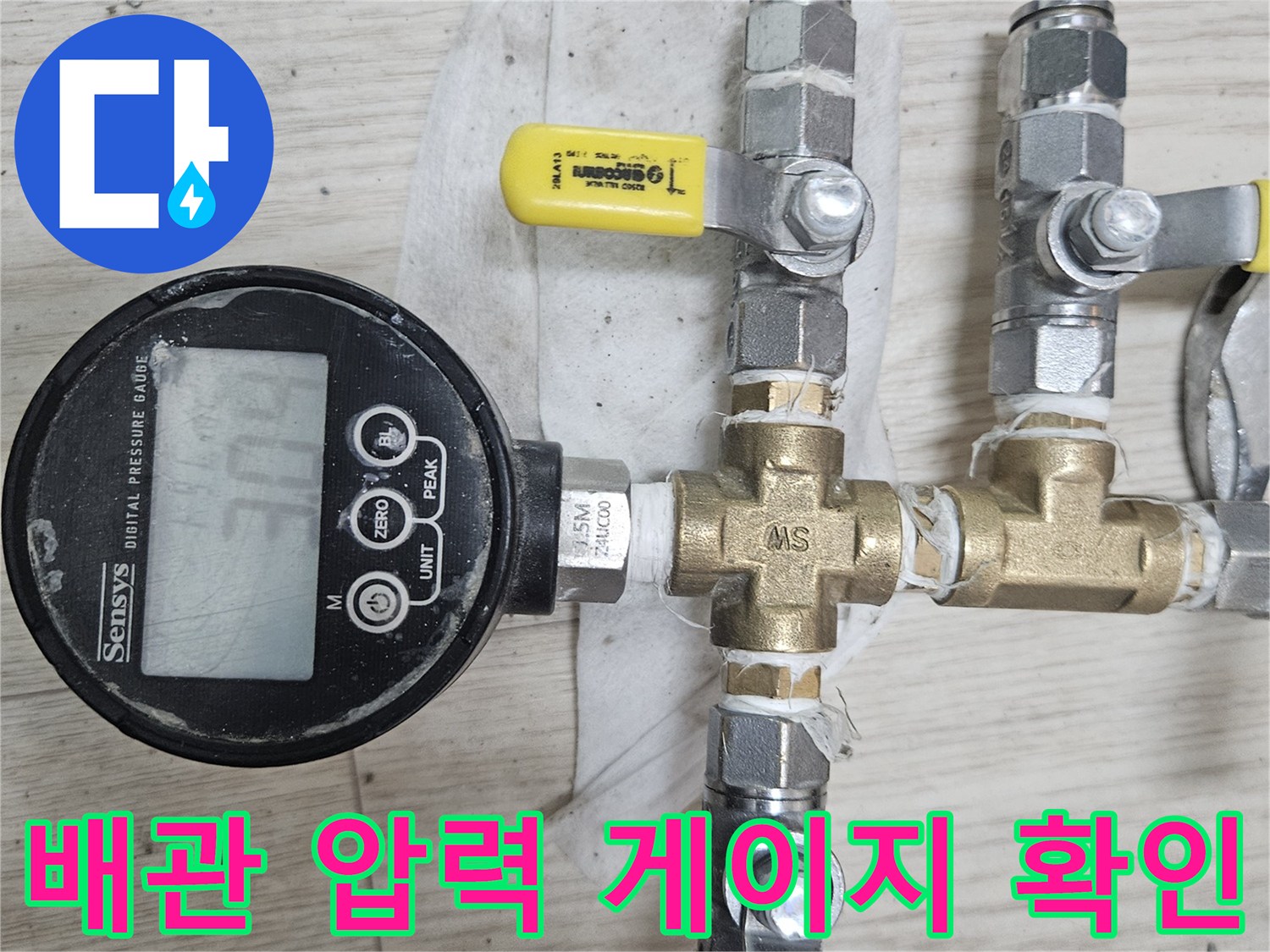 금속 배관과 노란색 밸브가 연결된 디지털 압력 측정 장치