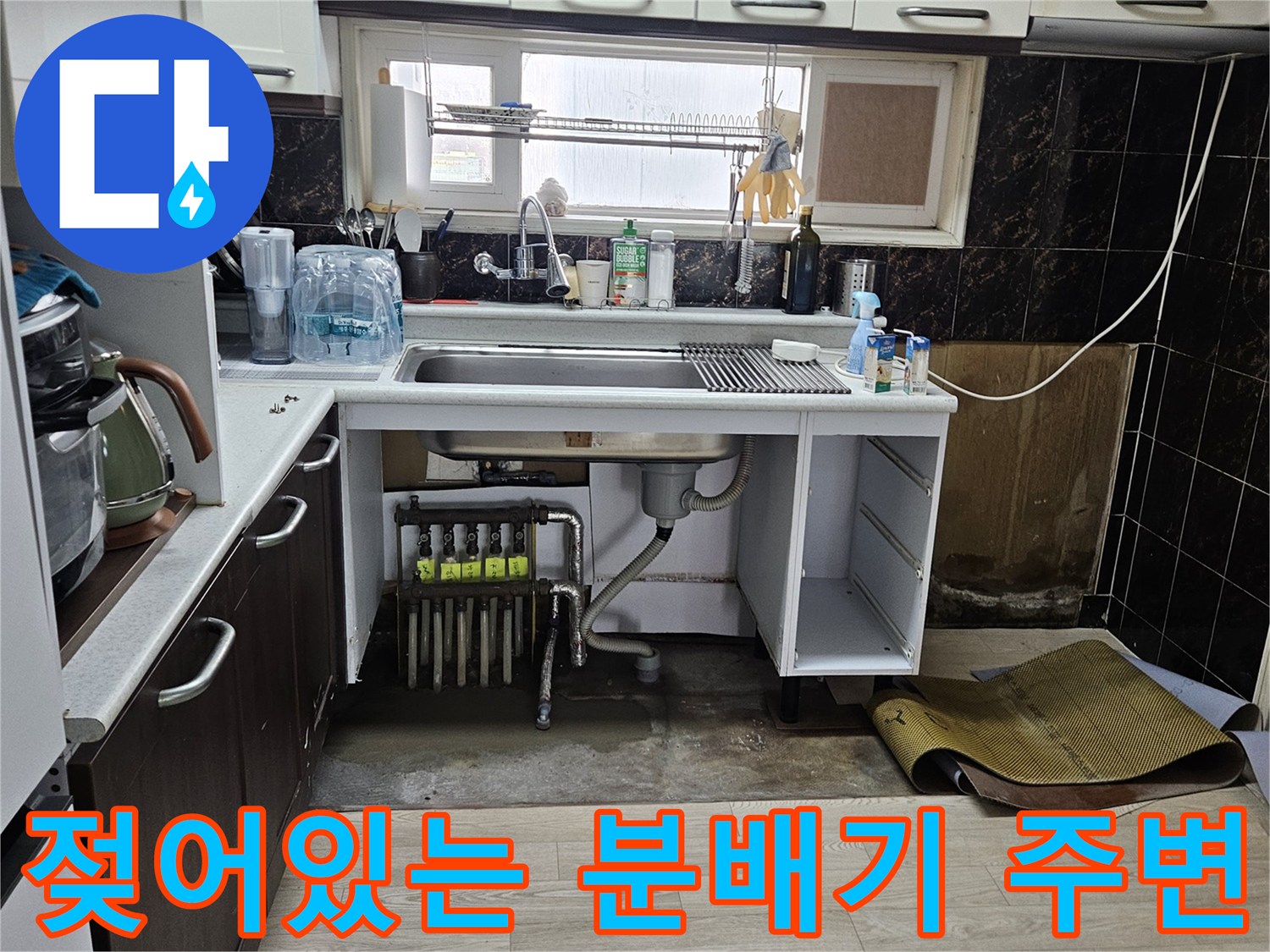 싱크대 밑 공간-물샘 현상으로 인해 젖어 있는 바닥과 노출된 배관 부속들