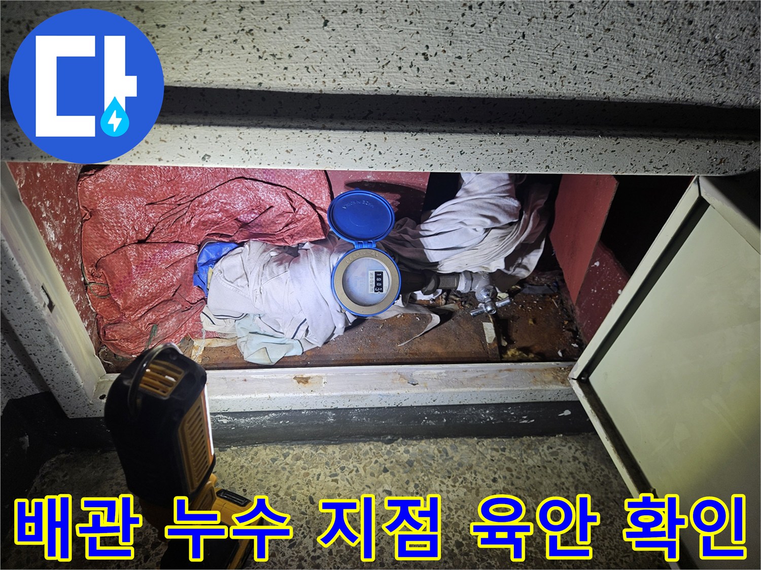 싱크대 아래 배관 주변의 젖은 바닥과 노출된 배관 부속품