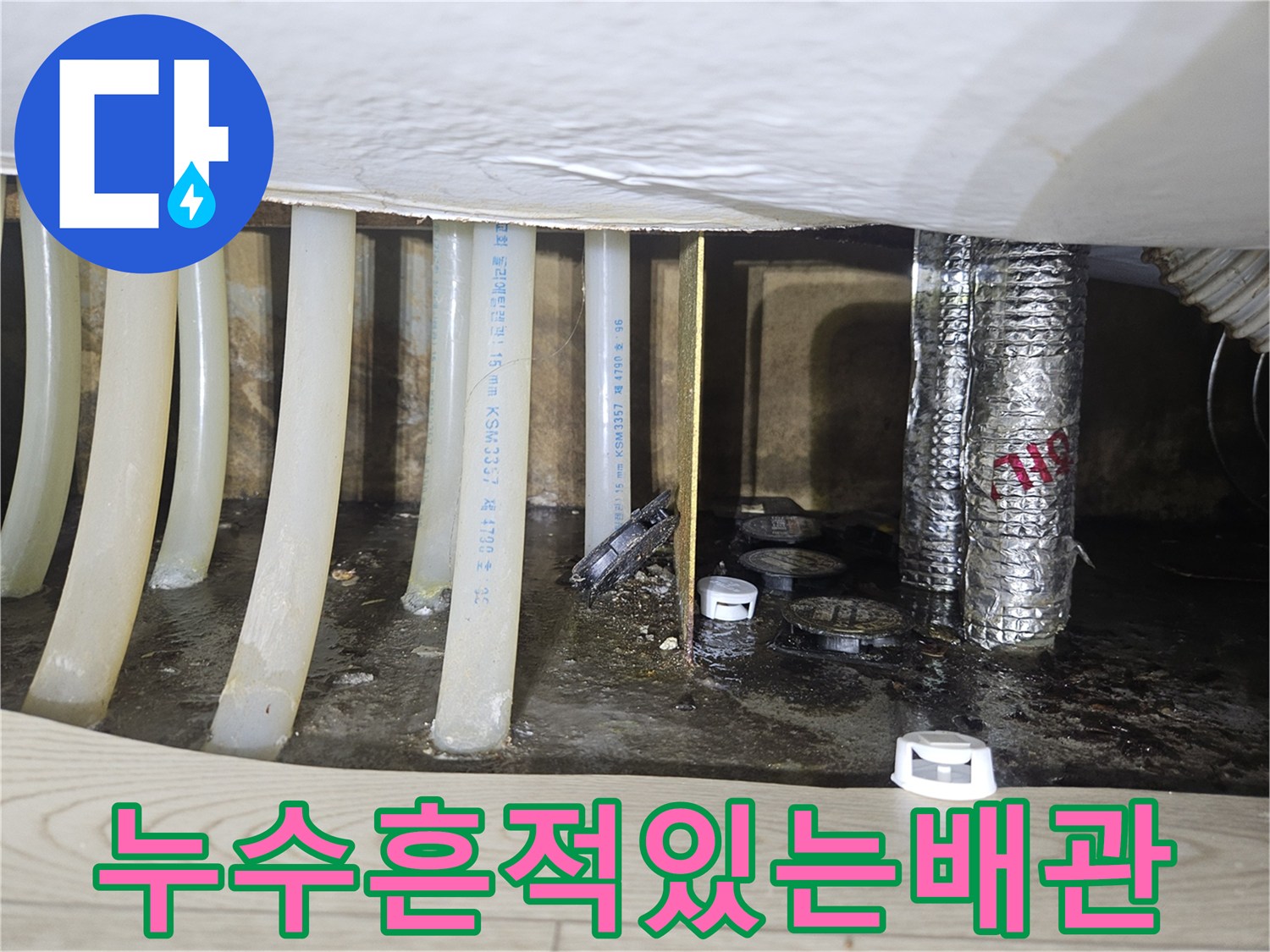 싱크대 하단 분배기 주변의 젖은 바닥과 배관들