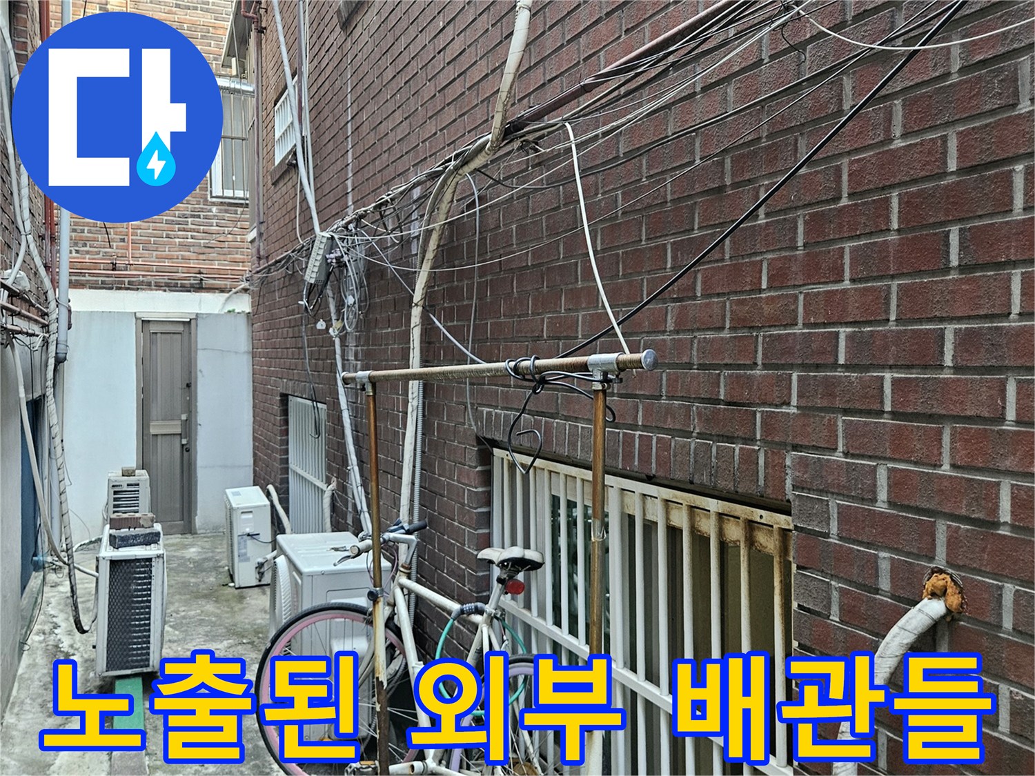 붉은 벽돌 외벽과 실외기 주변에 설치된 각종 배관 시설물