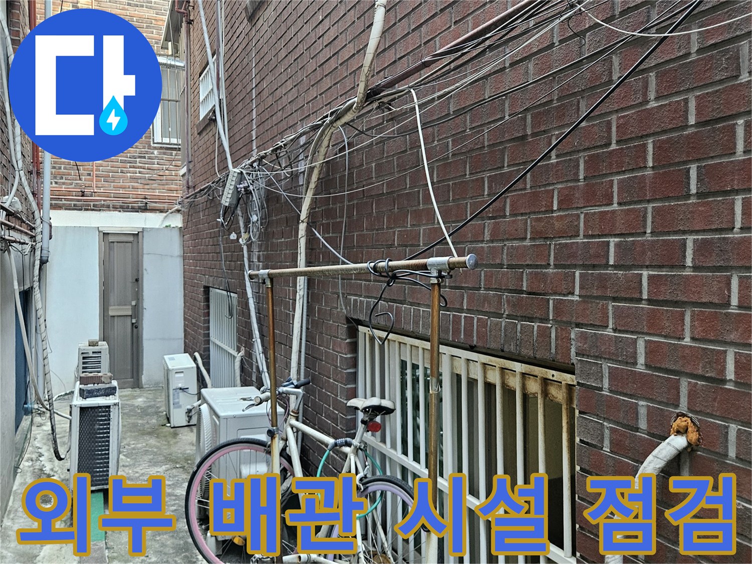 붉은 벽돌 외벽에 설치된 다양한 종류의 외부 노출 배관들