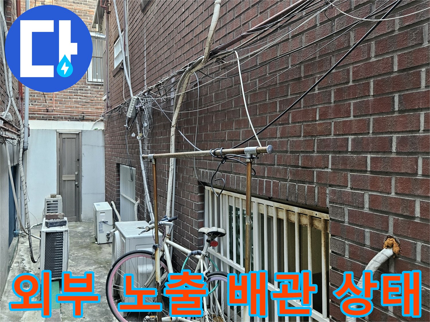 붉은 벽돌 외벽에 설치된 에어컨 및 급수용 배관 라인