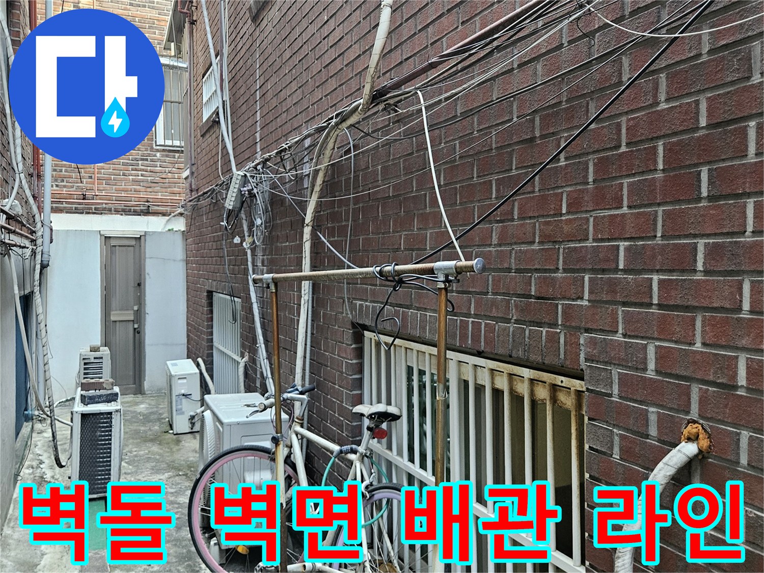 붉은색 벽돌 외벽에 설치된 노출형 수도 배관의 근접 촬영