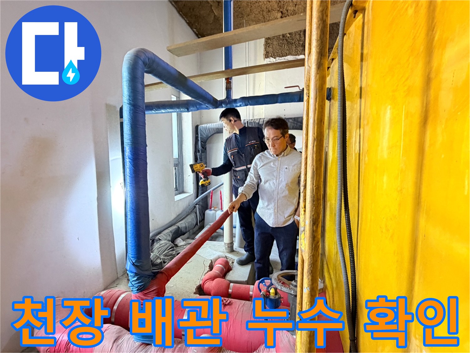 파란색과 분홍색 보온재가 입혀진 배관 사이에서 엔지니어가 점검을 수행하고 있습니다.