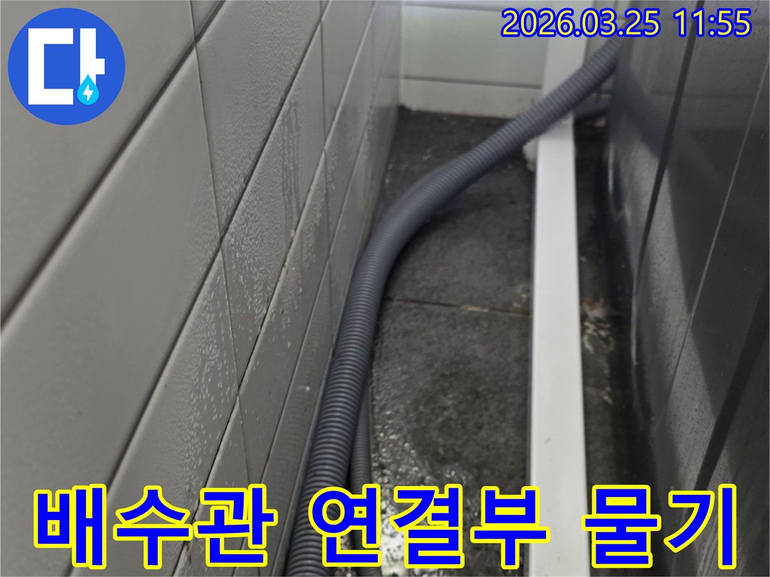 세탁실 바닥의-배수 호스 연결 부위 주변에-물이 고여있는-누수 현장 이미지입니다.