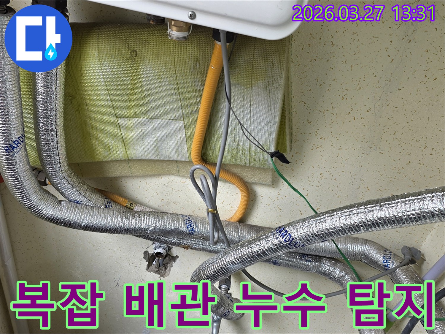 보일러-아래쪽의-복잡하게-얽힌-배관과-전선-연결-상태를-보여주며-누수-탐지를-위한-현장-조사-중입니다.