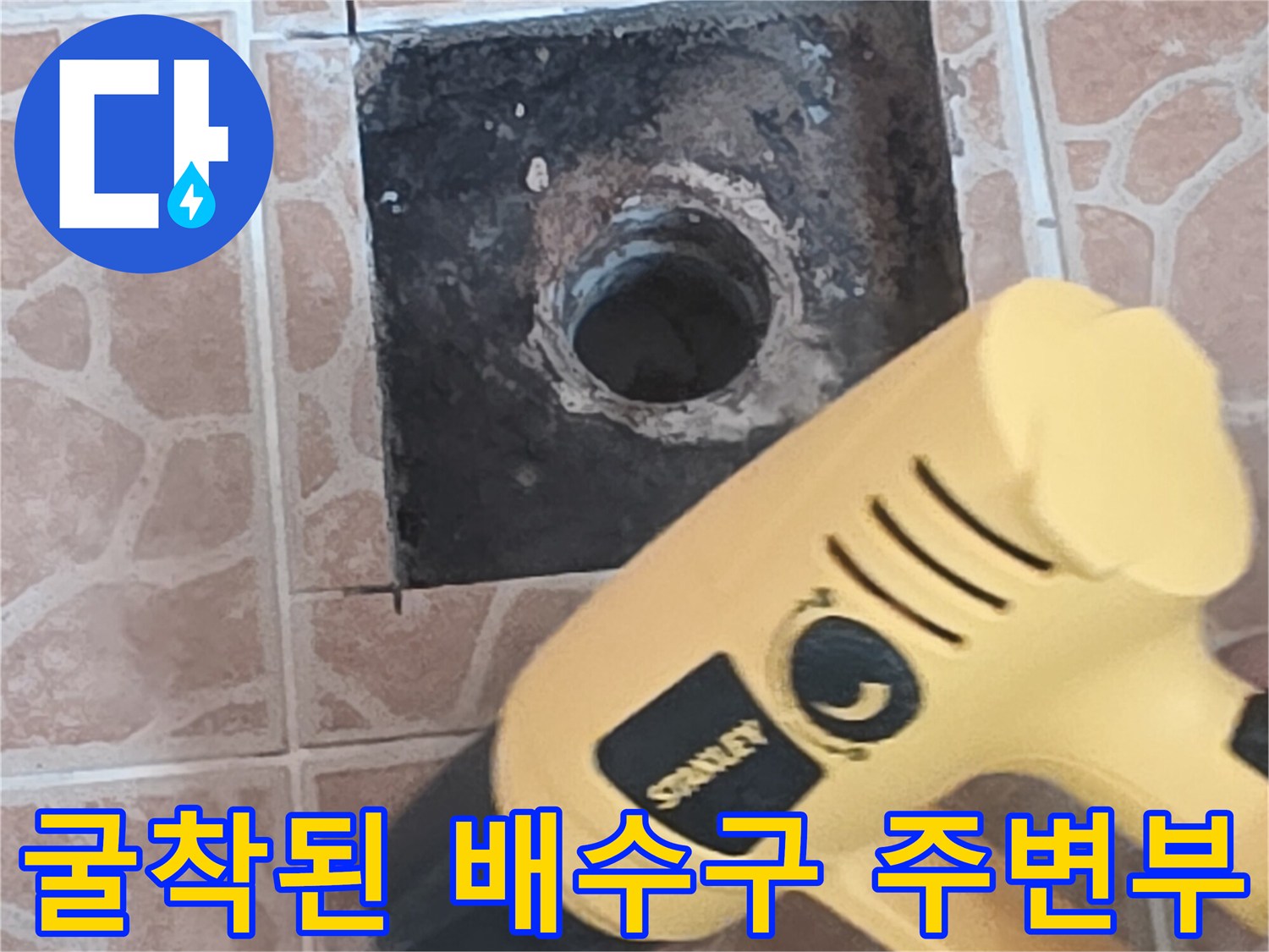타일이 제거되어 어둡게 드러난 배수 파이프 입구 영역