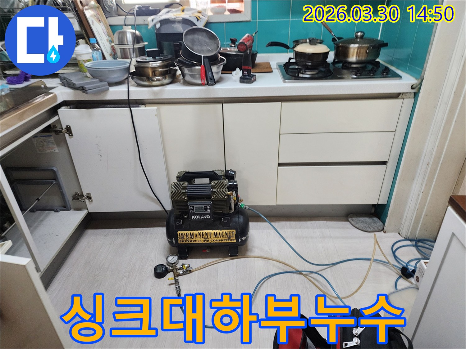 주방 싱크대 하부장 문이 열린 채-누수 탐지 장비가 설치되어-숨겨진 배관 누수 원인을 찾고 있습니다.