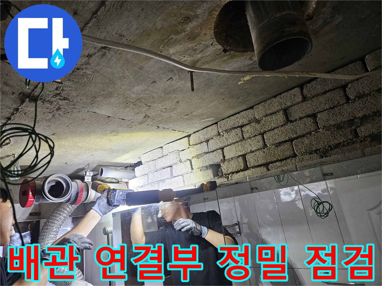 어두운 천장 공간의 배관을 손전등으로 비추는 엔지니어의 모습