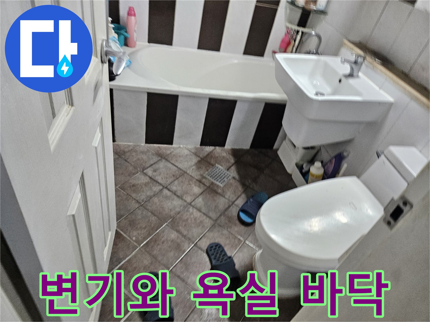 욕실 양변기 주변의 타일 바닥과 세면대 하부 공간을 보여줍니다.