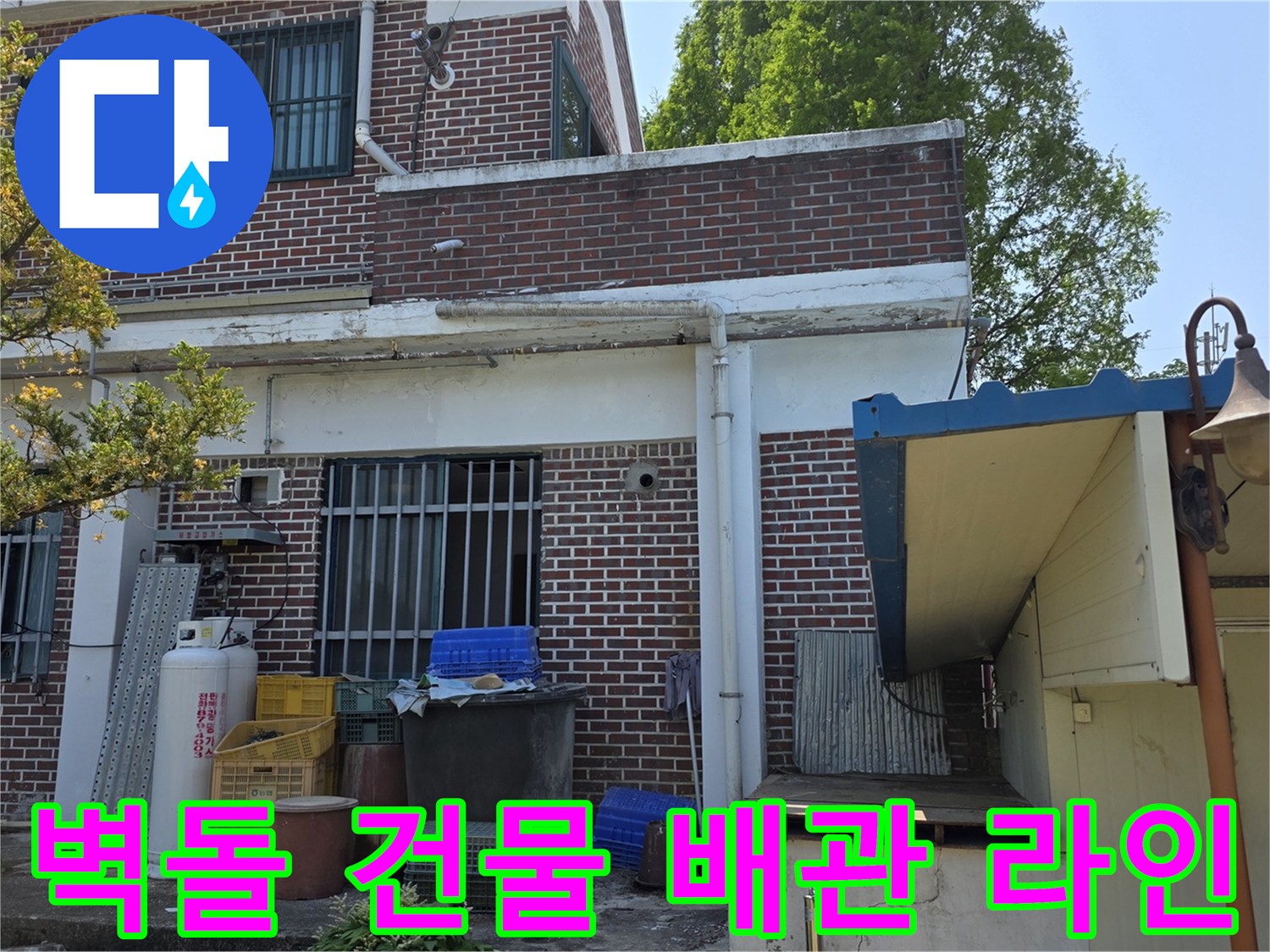붉은 벽돌 외벽에 설치된 외부 수도 배관과 건물의 모습입니다.