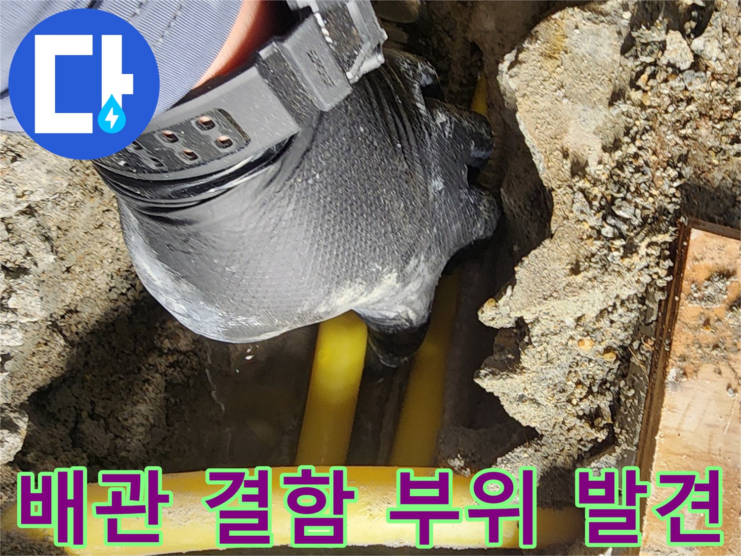 노란색 배관 주위의 젖은 흙과 파헤쳐진 콘크리트 바닥
