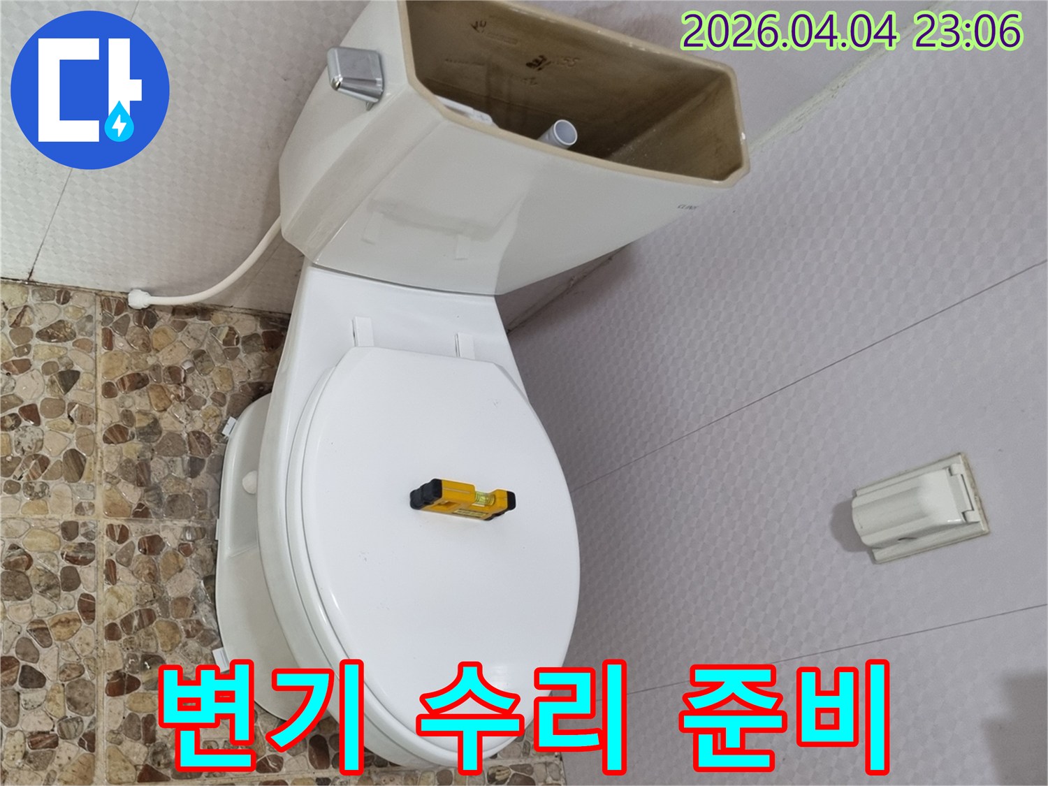 변기 물탱크가 열려 내부 부품이 노출된 상태로-수평계가 변기 시트 위에 놓여-변기 수리를 위한 준비가 완료되었습니다
