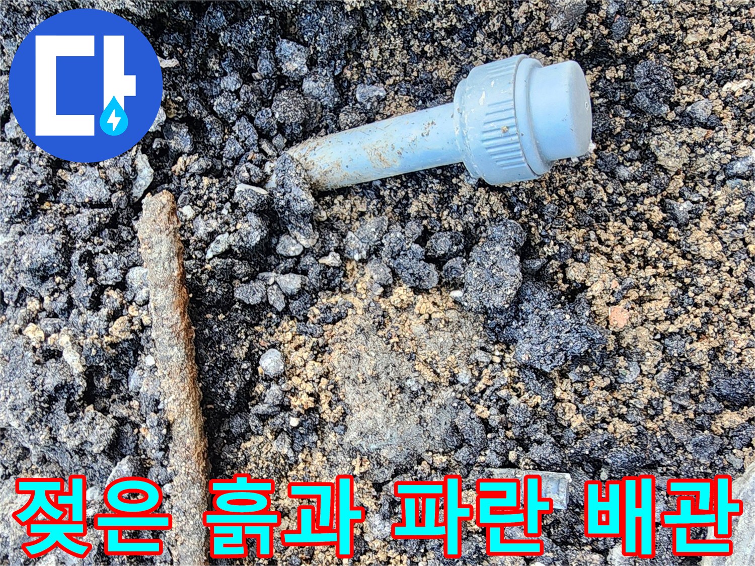 아스팔트 층 아래에 드러난 물에 젖은 토사와 배관 부속