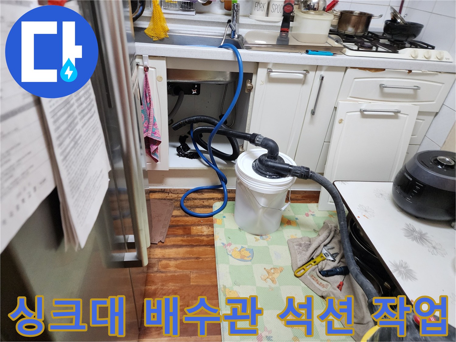 싱크대 하부장 아래 배관과 연결된 석션 호스 및 수거통