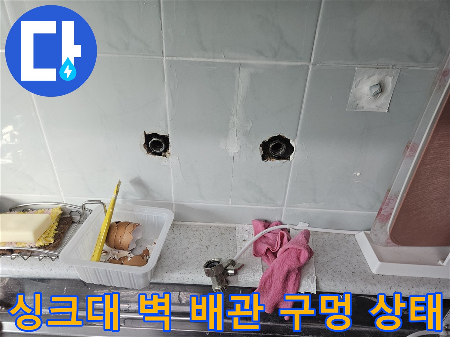 누수 확인을 위해 노출된 싱크대 하부 타일벽의 배관 연결 통로
