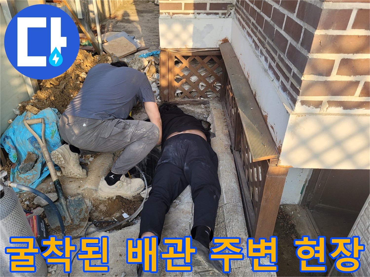 주택 계단 아래 흙을 파내어 드러난 배관 주변의 작업 환경