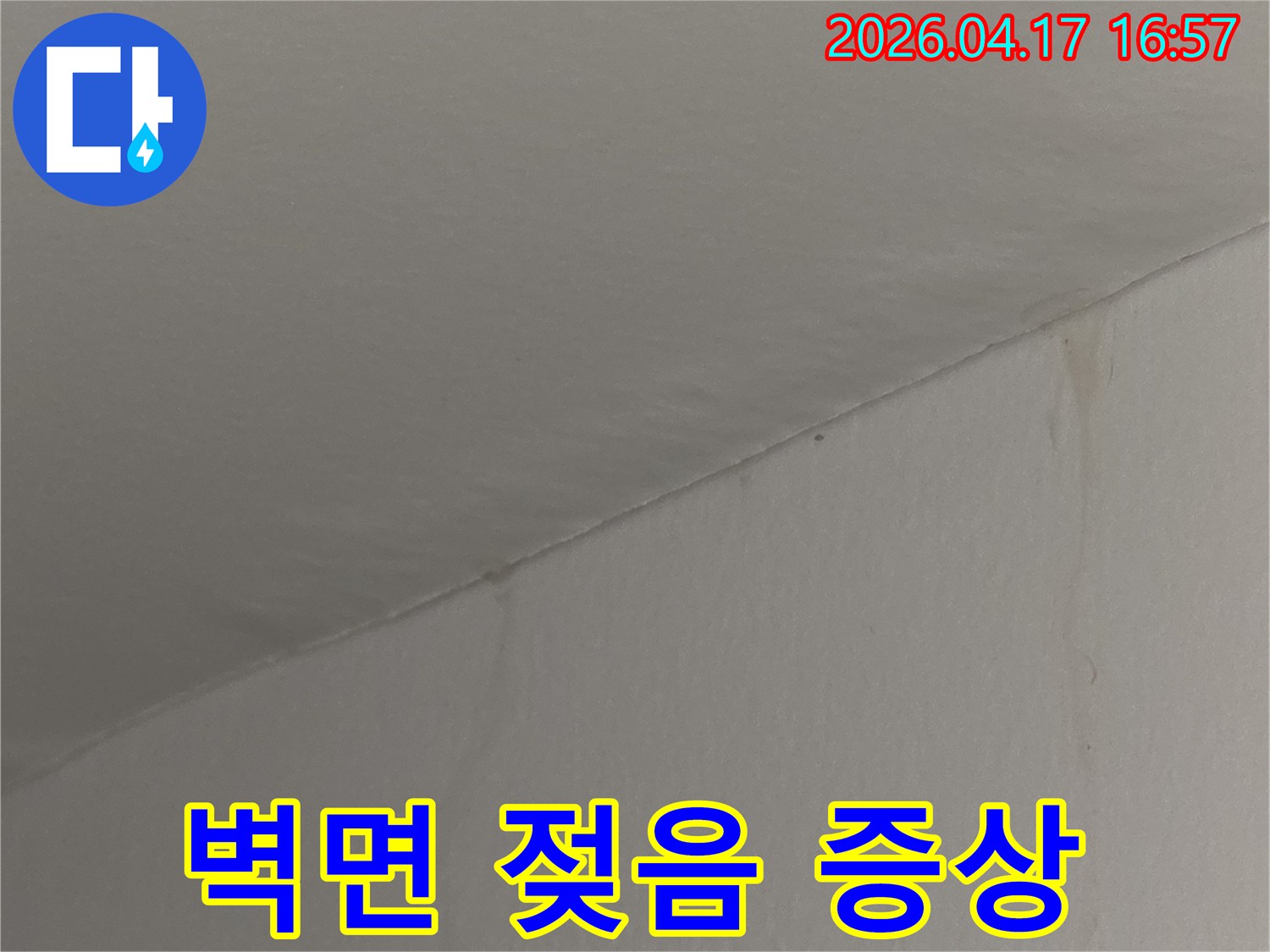 천장과 맞닿은 벽면이-물에 젖어 어둡게 변색된 누수 증상 사진입니다