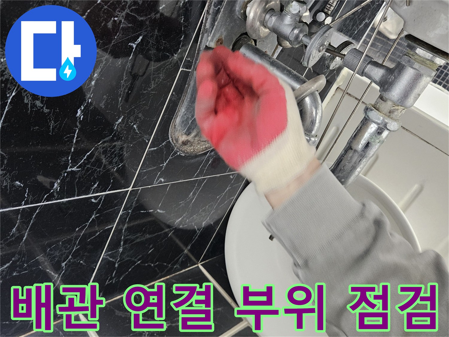 장갑을 낀 손으로 싱크대 하부 배관의 체결 상태를 만져보는 사진