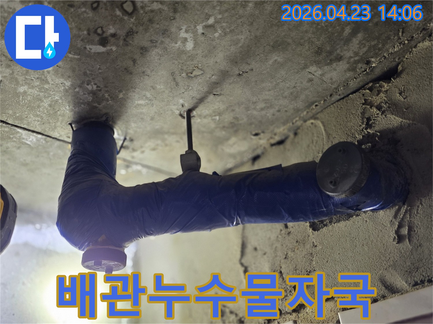 보온재로 감싸진 배관 아래-천장 콘크리트가 젖어있는-누수 현장의 클로즈업 사진-오래된 물 자국이-선명하게 보이는-문제 지점