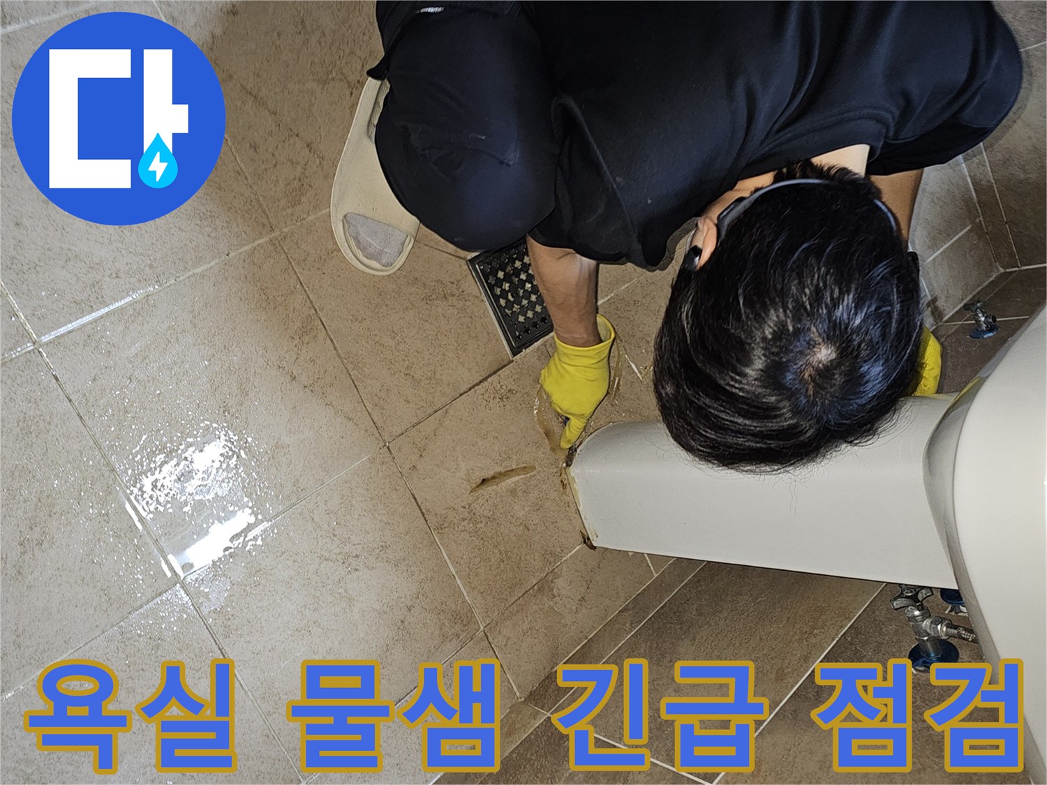 전문 엔지니어가-노란 장갑을 끼고-욕실 바닥의 젖은 타일과-세면대 하단부를-집중적으로 관찰하며-긴급 누수 지점을 파악하고 있습니다