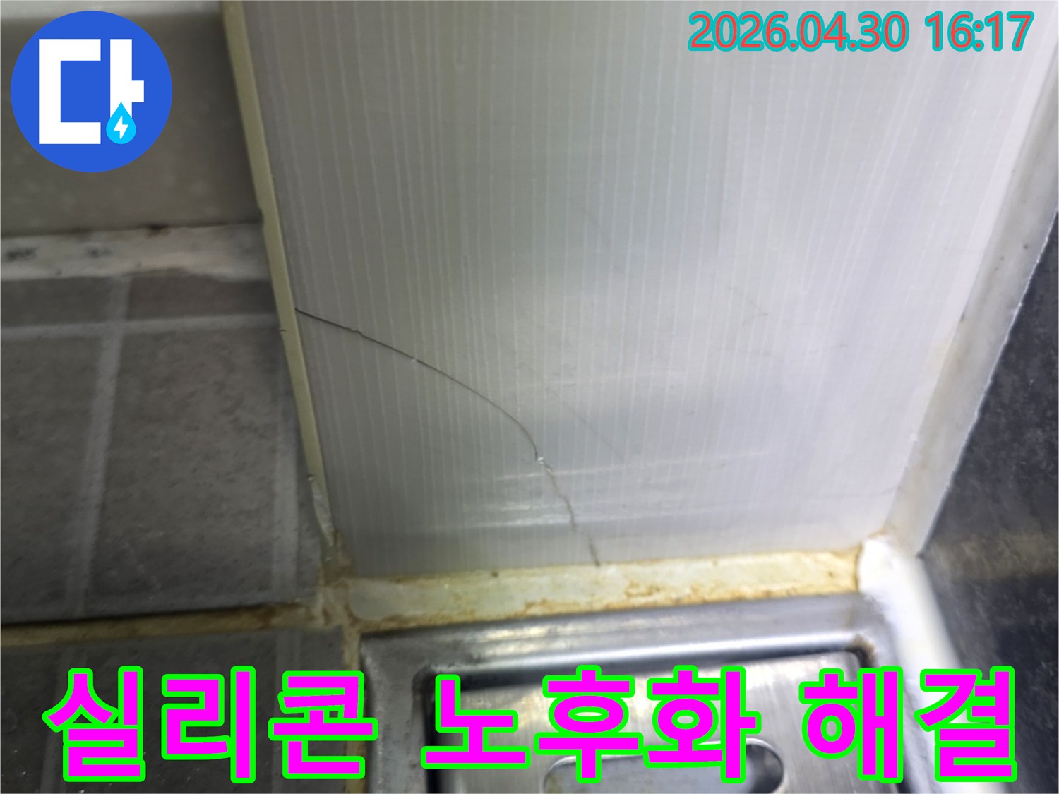욕실 바닥과-벽면의 경계에 위치한-실리콘 마감재가-노후되어 갈라진-누수 발생 지점을 보여주는 이미지입니다.