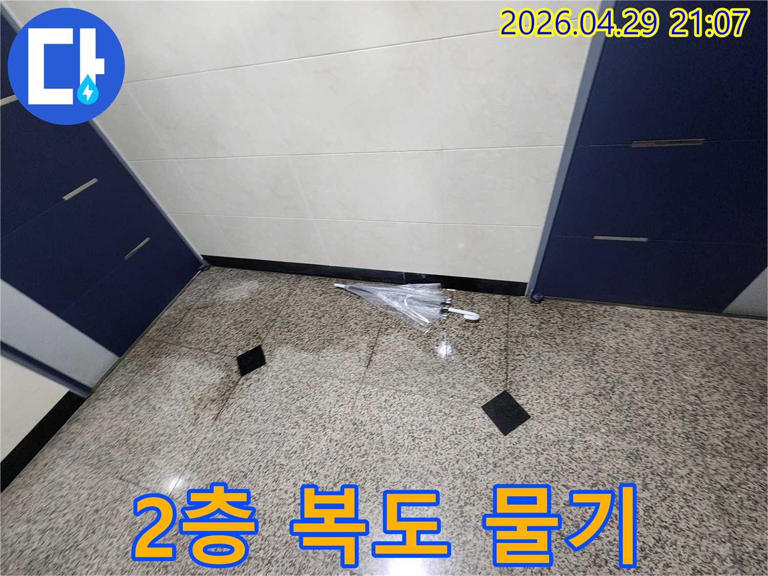 물기가 가득한-2층 복도 바닥과-젖은 우산이 놓인-누수 현장