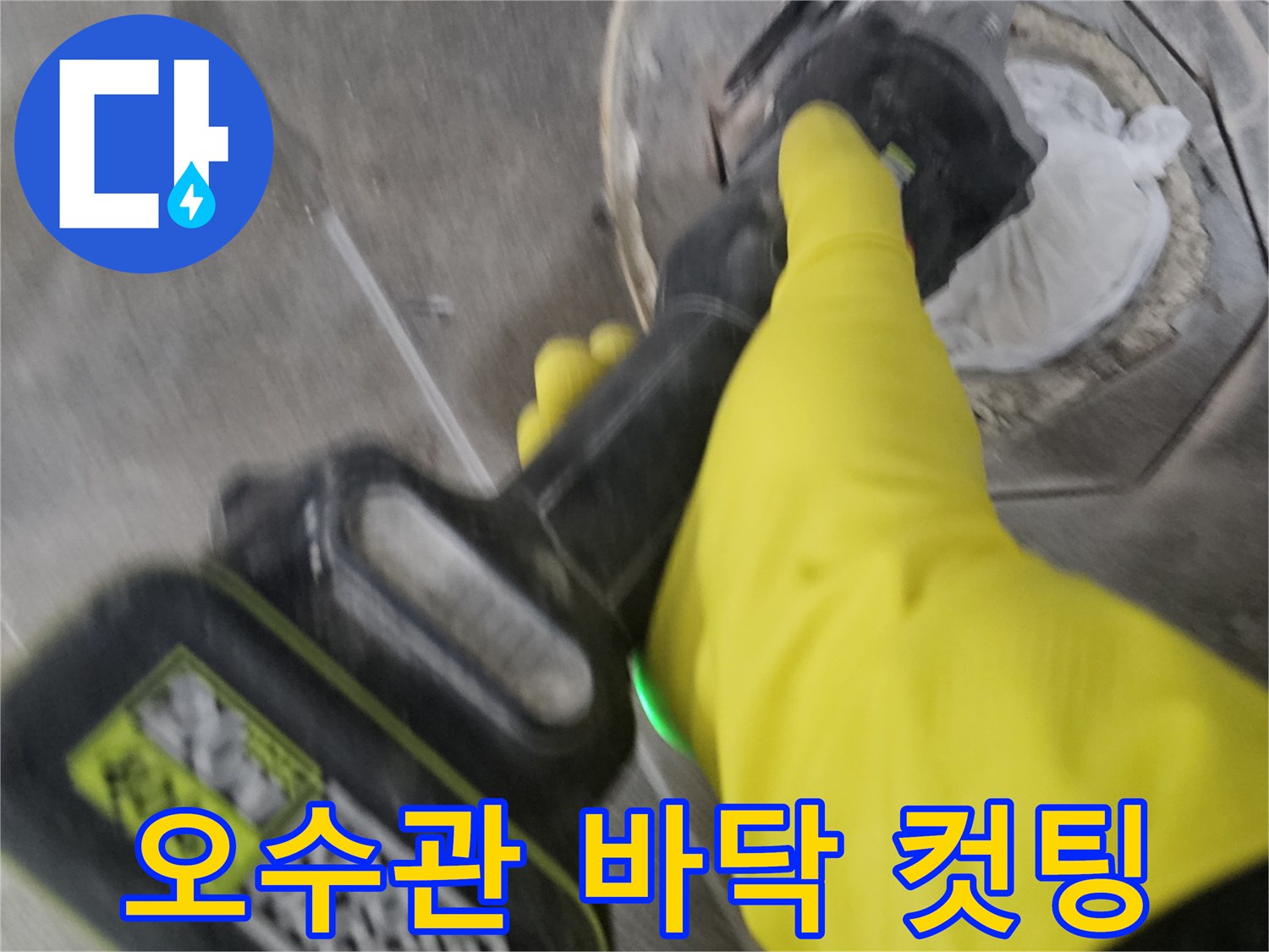 노란색 장갑을 착용한-작업자가-전동 커팅기로-오수관 주변의 바닥을-정밀하게 컷팅하여-개방하는 모습입니다.