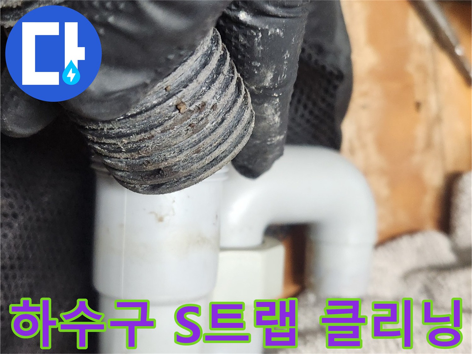 작업자가 검은 장갑을 끼고-오염된 S트랩 배관을 분리하여-내부 청소를 진행하는 상세한 모습입니다
