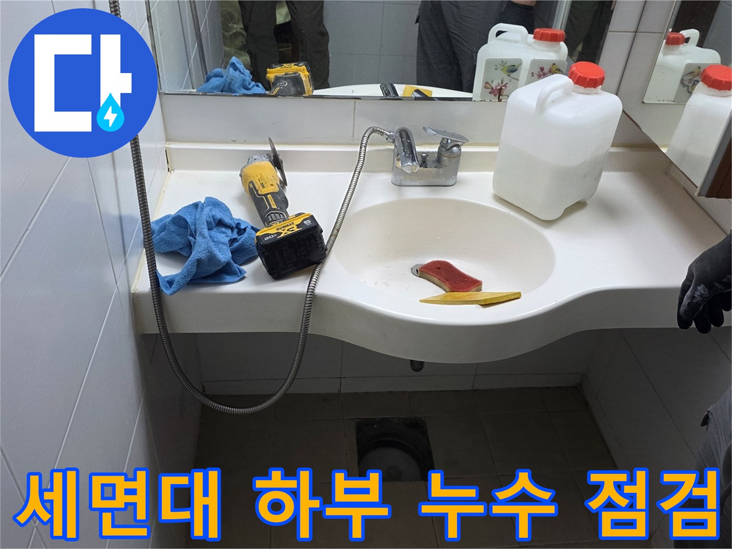 세면대 아래쪽 배관 주변에 놓인 작업용 도구와 용액
