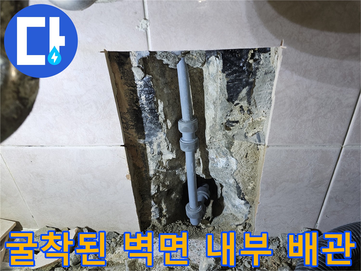 벽면 타일 아래에 노출된 세면대 연결 배관과 부속품