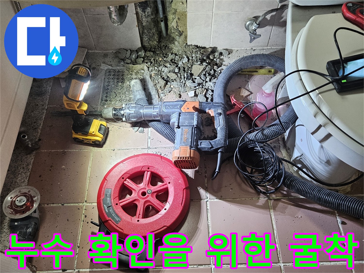 화장실 바닥 타일을 제거하고 배관 연결부를 찾기 위해 작업 중인 모습