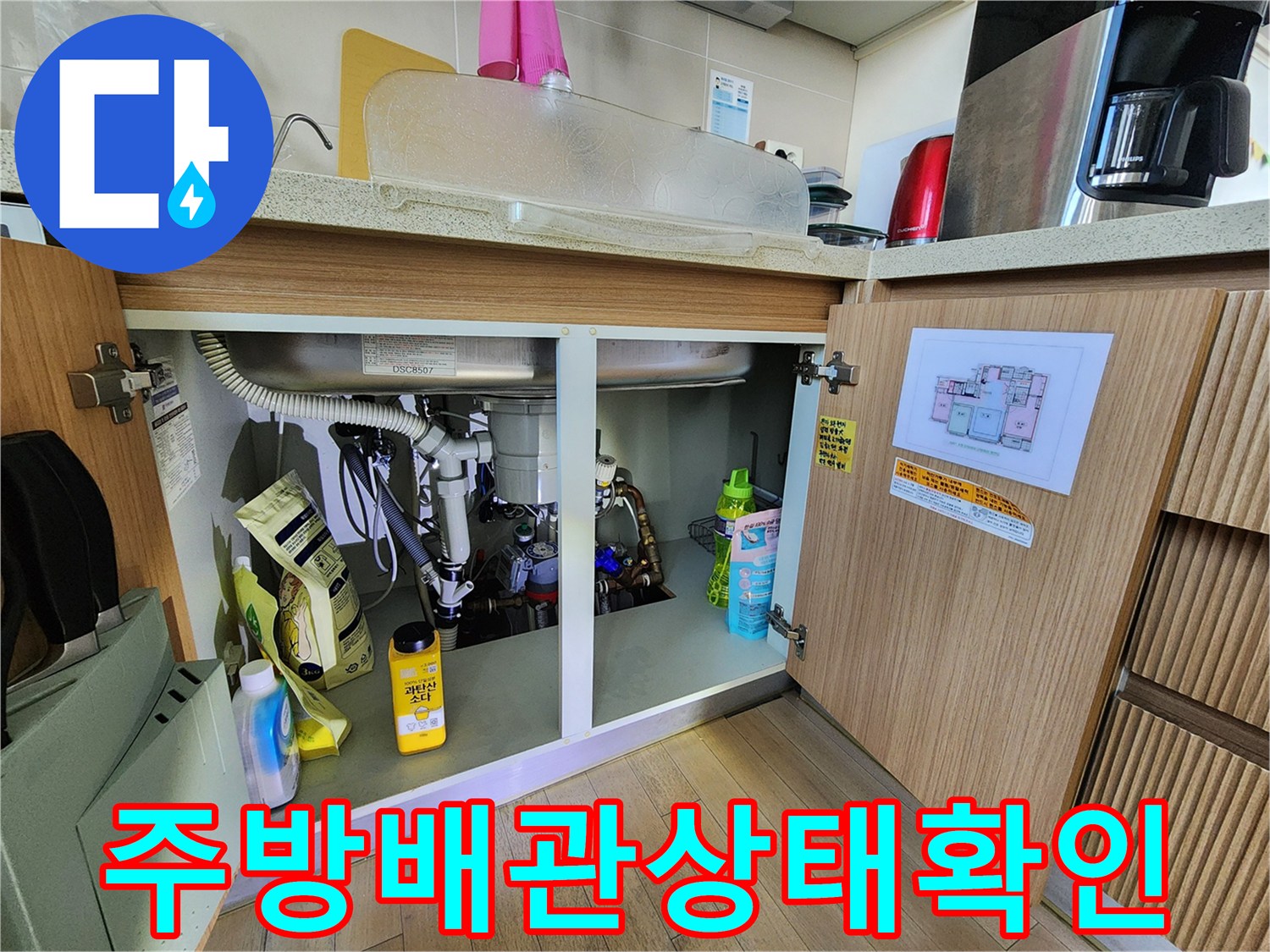 싱크대 하부장 내부의 배수 호스와 주변 집기들