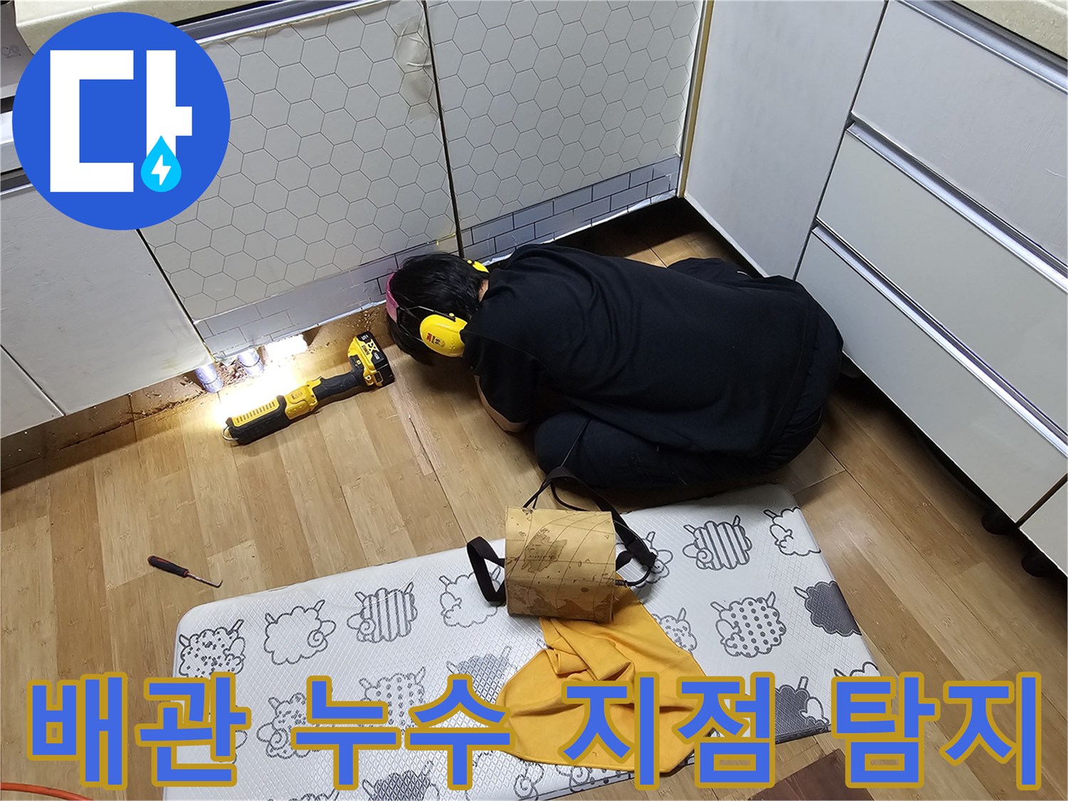 싱크대 하단 배관의 연결 부위를 정밀하게 조사하는 엔지니어