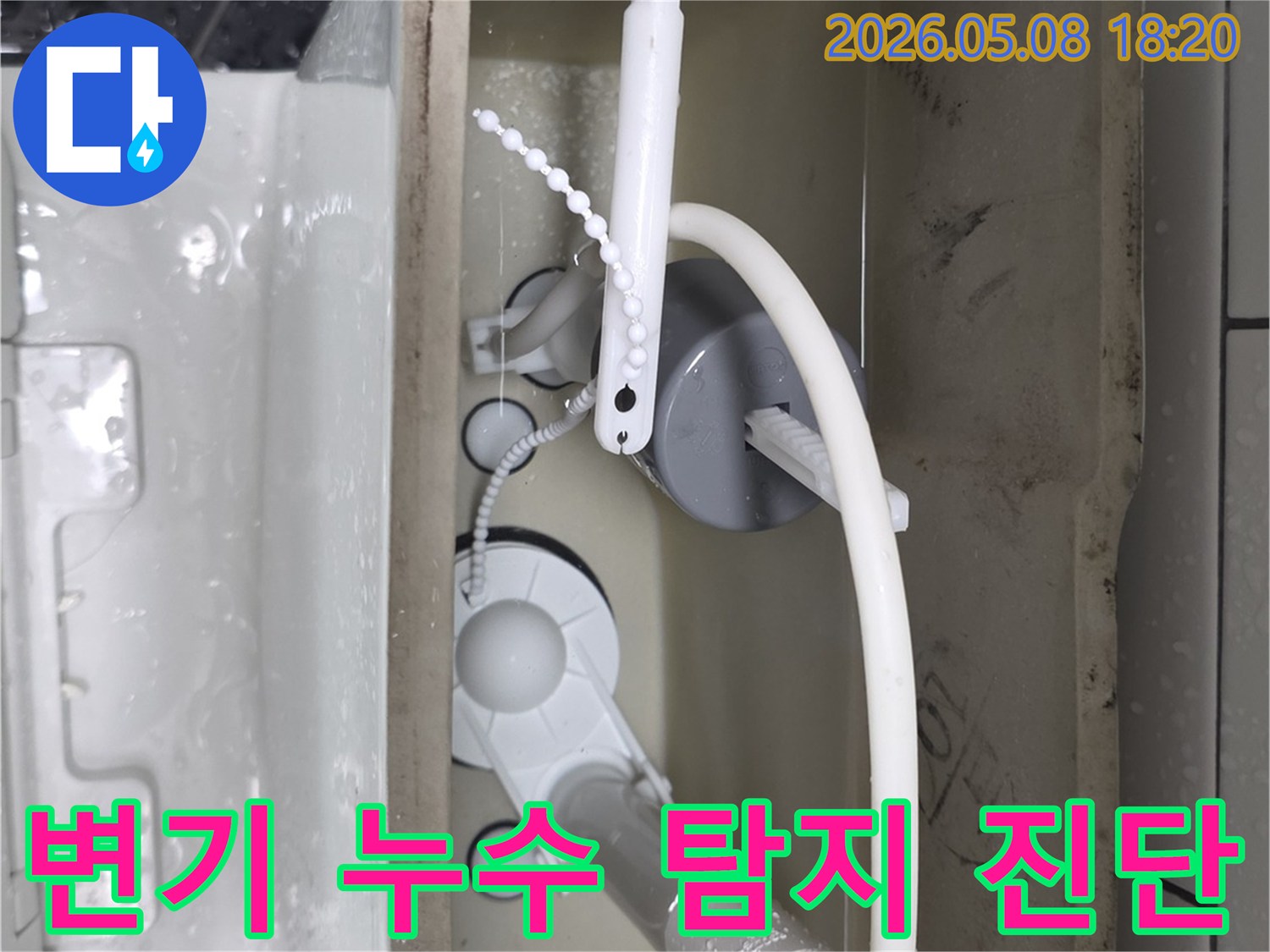 변기 물탱크 내부의 급수 밸브와 배수 밸브를 면밀히 관찰하여-미세한 누수 지점을 탐지하고 원인을 진단하는 모습