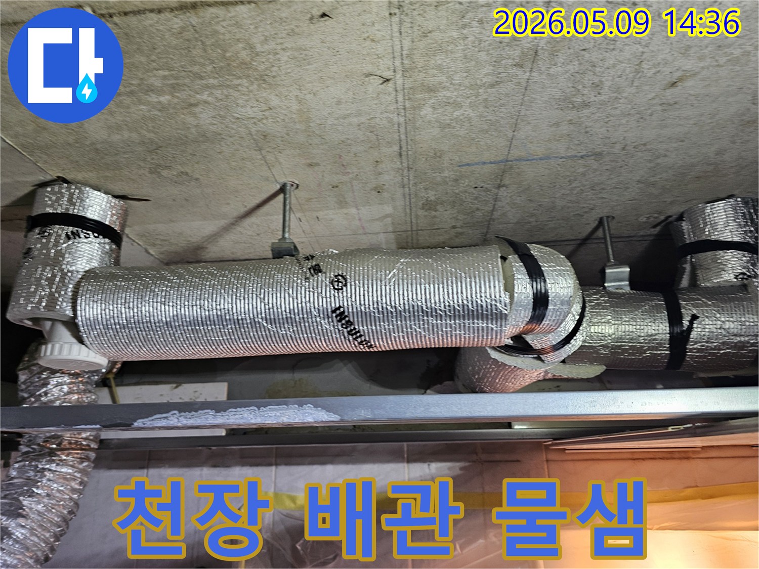천장에 설치된 단열 처리된 배관 아래 금속 선반에 하얗게 굳은 물 자국