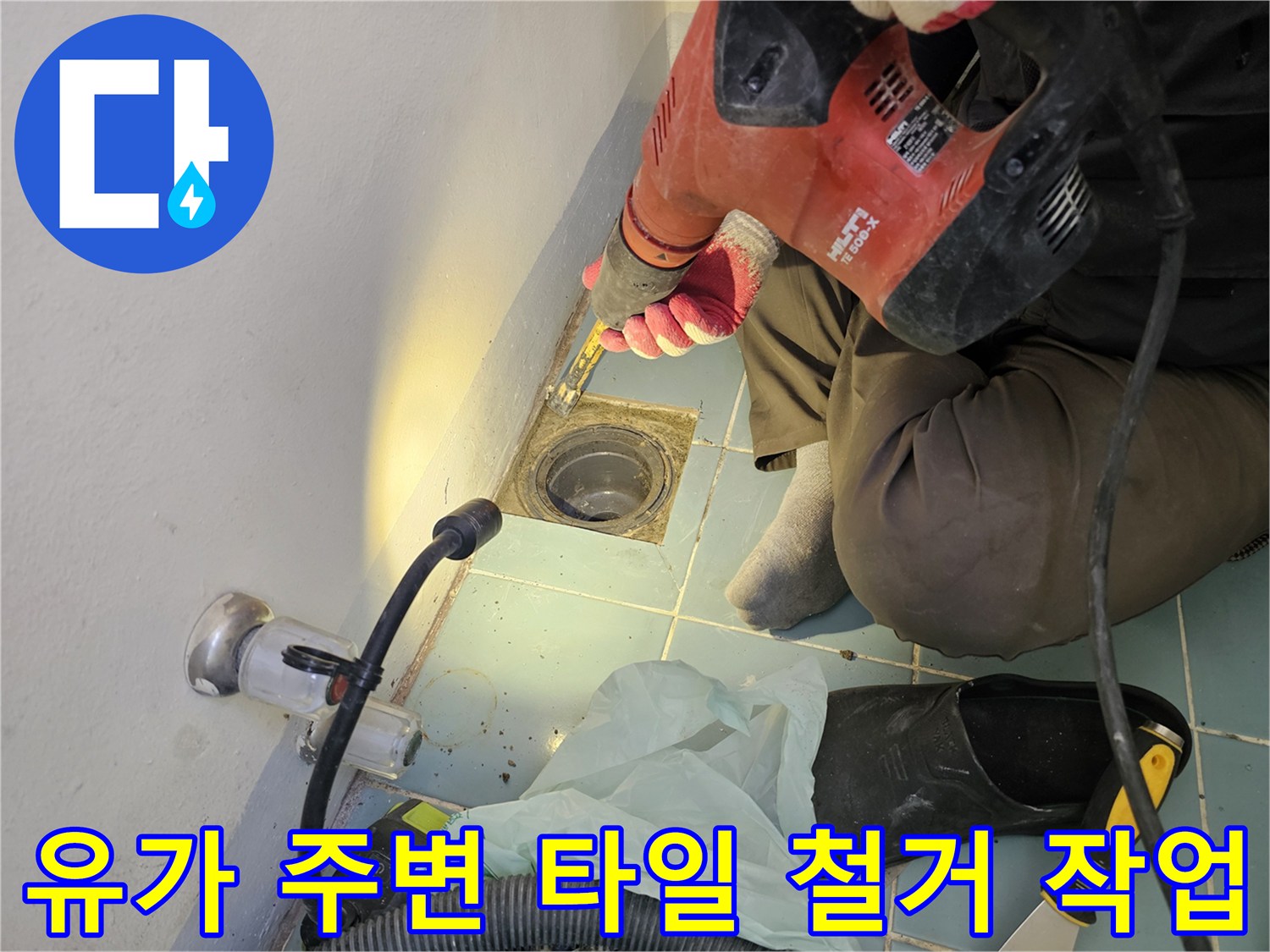 함마드릴을 사용하여-배수구 주변의 노후된 타일을 제거하는 모습