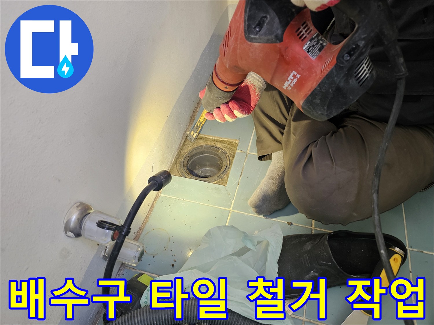 함마드릴을 사용하여-세탁실 배수구 주변의 타일을 제거하는 모습