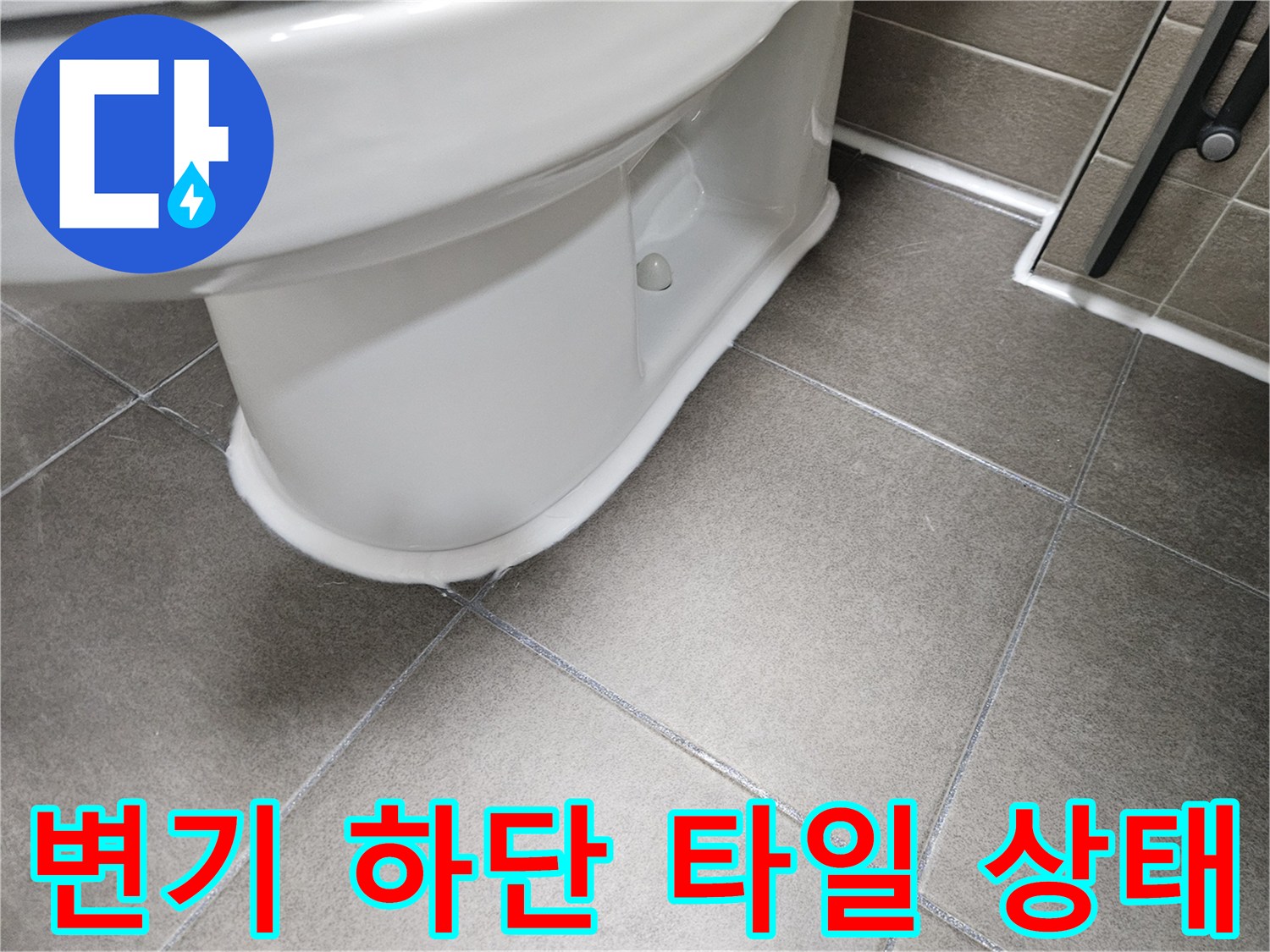 변기 밑부분과 회색 타일의 접합부 모습
