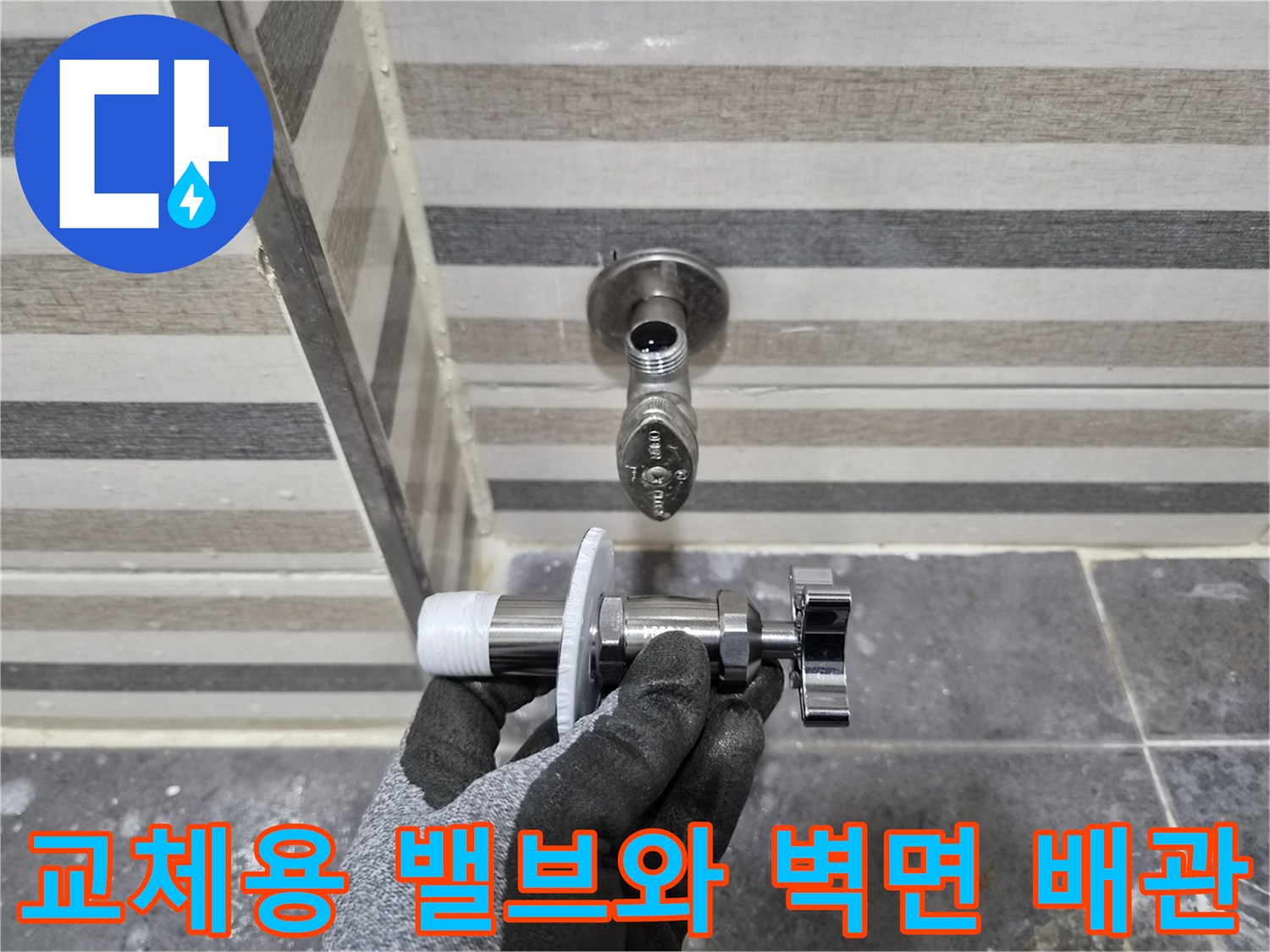 벽에 고정된 급수 밸브 및 교체를 위해 들고 있는 수전 부속