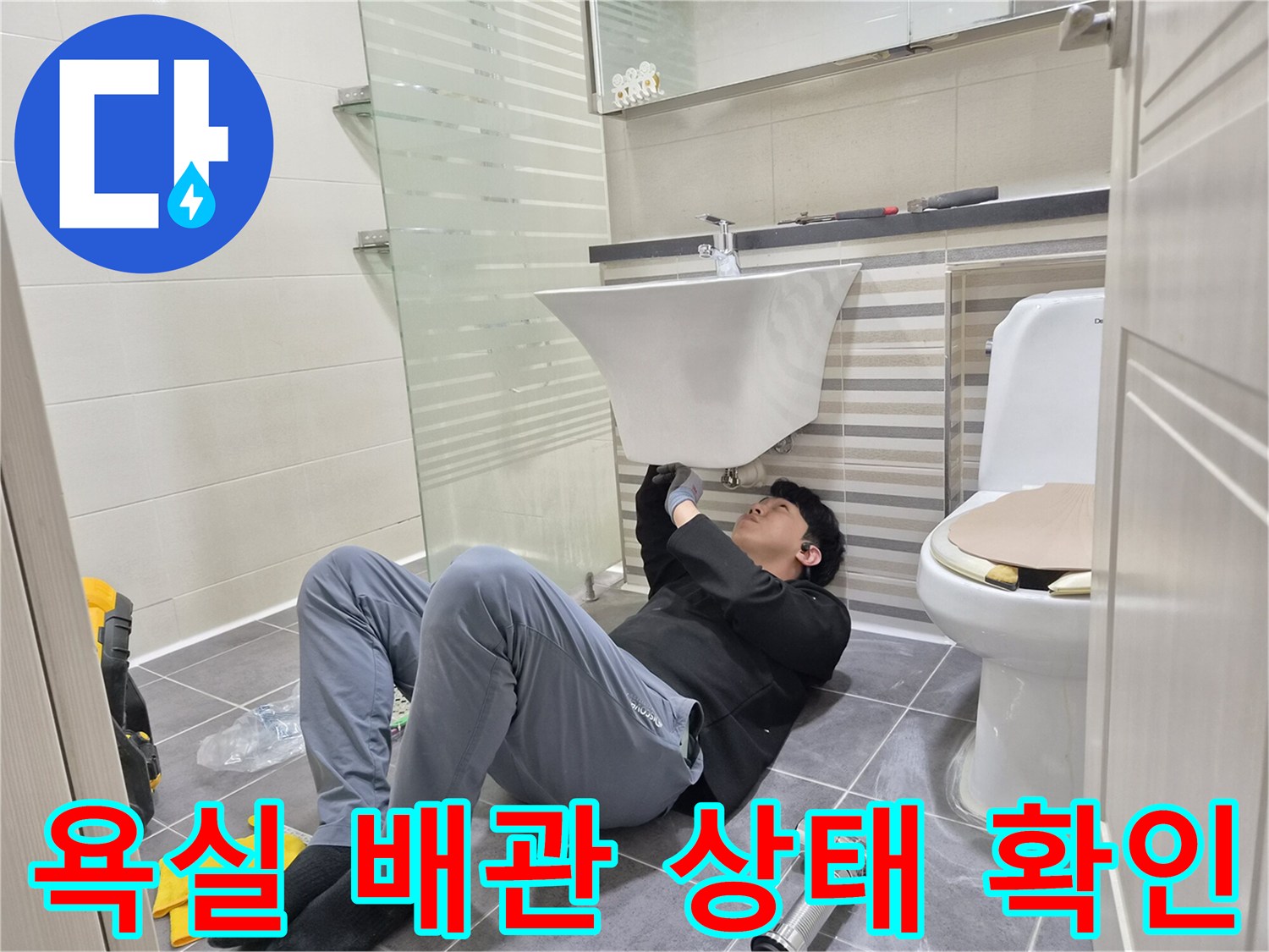 세면대 하단 배관 연결부의 누수 지점을 찾는 작업 현장