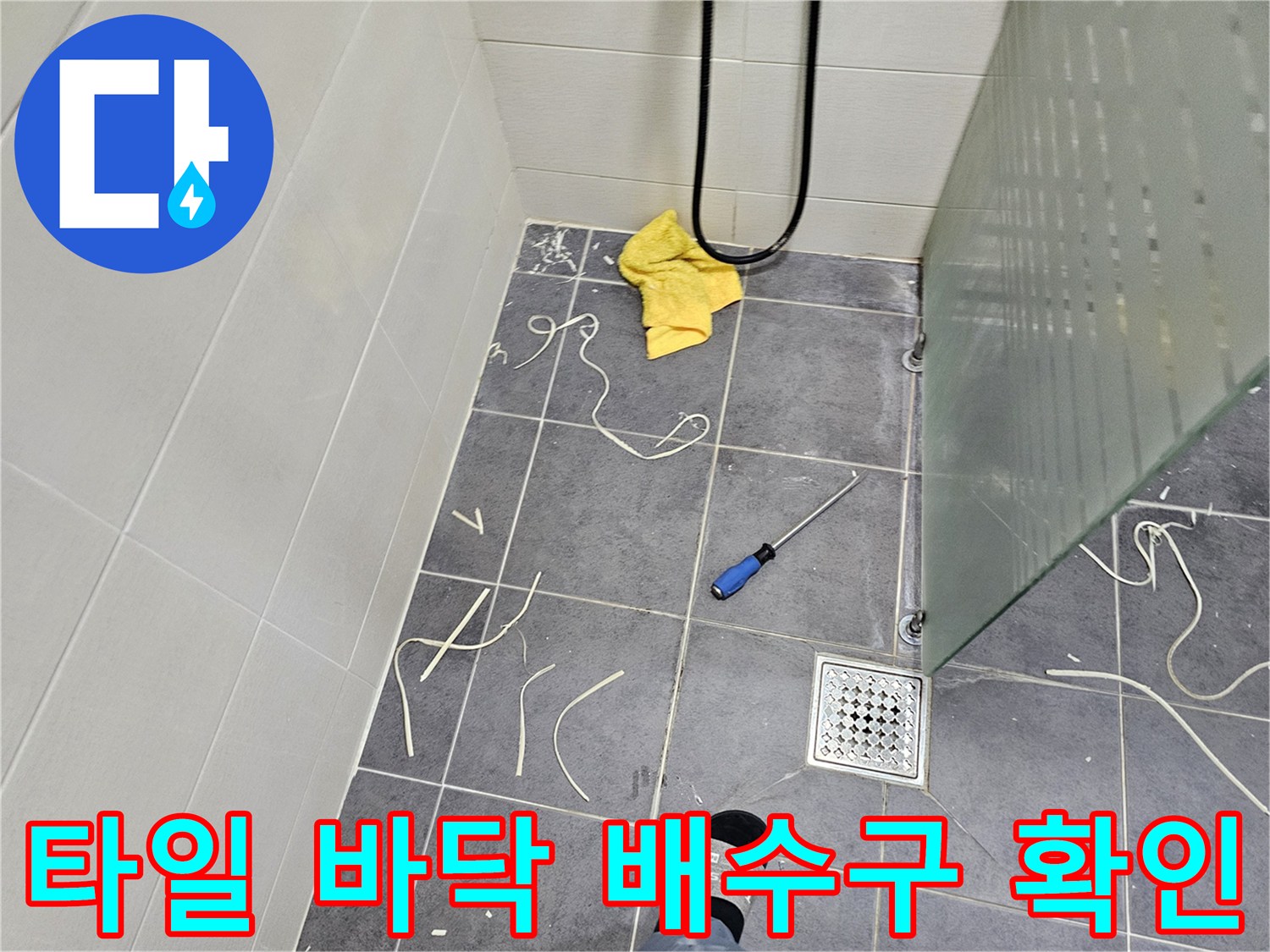 화장실 배수구 주변의 타일 상태와 작업 도구들