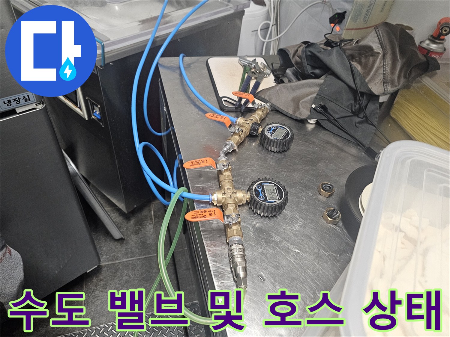 주방 싱크대 하부의 밸브와 파란색 유연한 호스 연결 부위