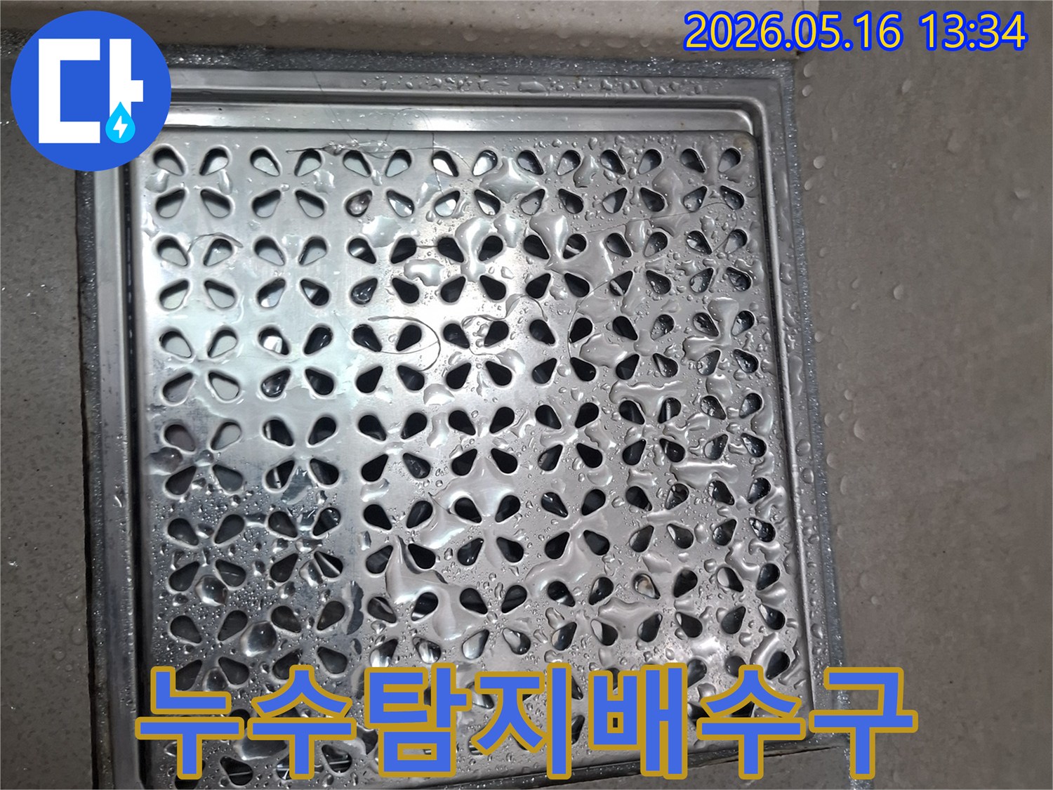 스테인리스 재질의-꽃무늬 패턴-배수구 덮개와 주변 물기입니다.