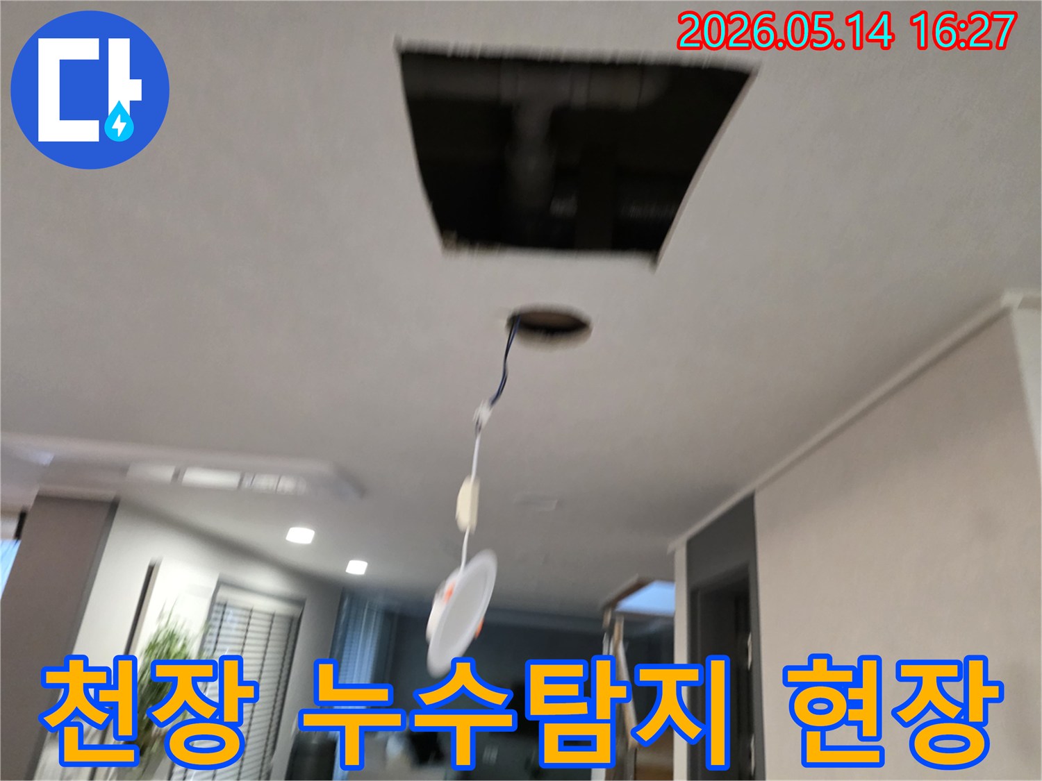 천장에서 발생한 누수 원인을 찾기 위해 개방된 천장 내부와-배관-그리고 매달린 조명 기구의 모습입니다.