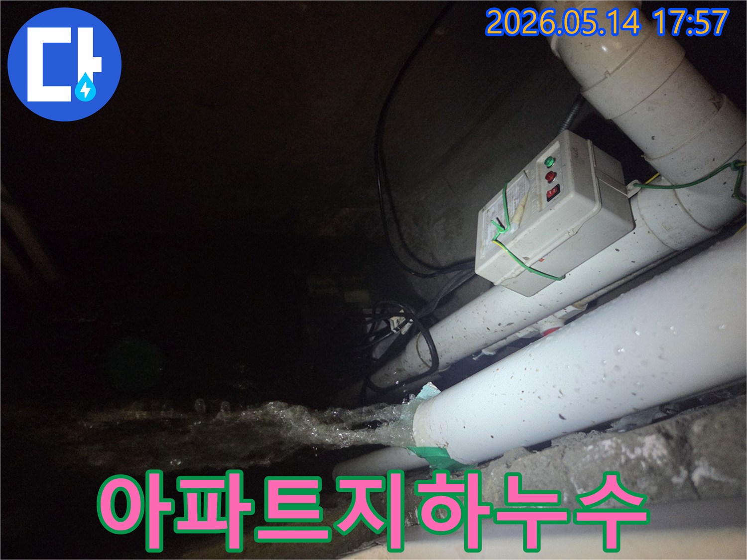 어두운 지하 공간에서-파이프에서 물이 강하게 뿜어져 나오는-아파트 지하 누수 현장을 보여주는 사진입니다-전기 제어 박스와 배관들이 함께 보입니다.