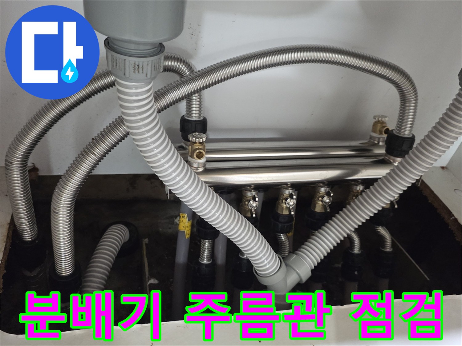 싱크대 하부장 내부-분배기에 연결된 은색 자바라 배관의 정렬 상태와 누수 여부 확인
